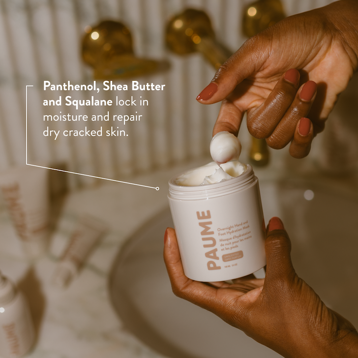 Hands scooping cream from a white PAUME jar in a softly lit bathroom setting, with text overlay highlighting moisturizing ingredients like panthenol, shea butter, and squalane.