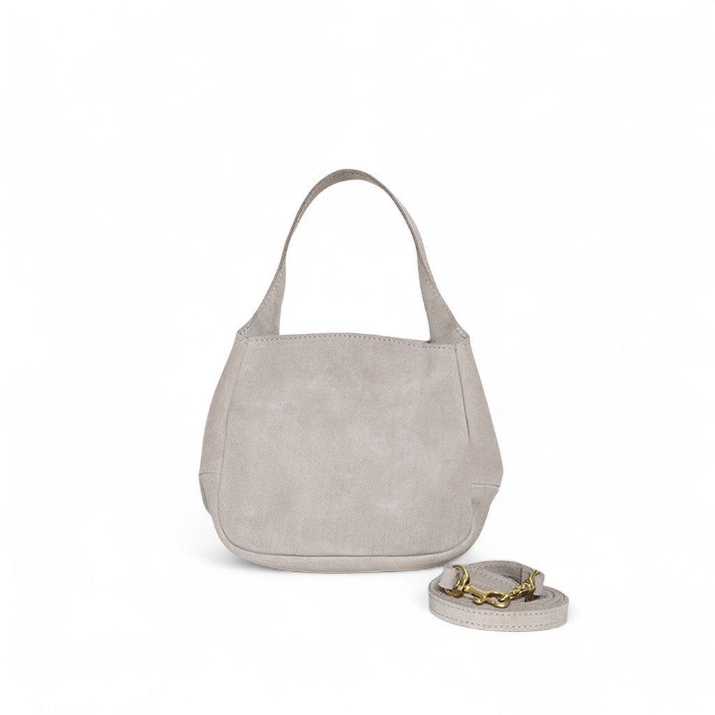 Compact taupe suede handbag with a softly structured, curved silhouette and short top handle, finished with a detachable strap featuring gold hardware and a clean, understated design.