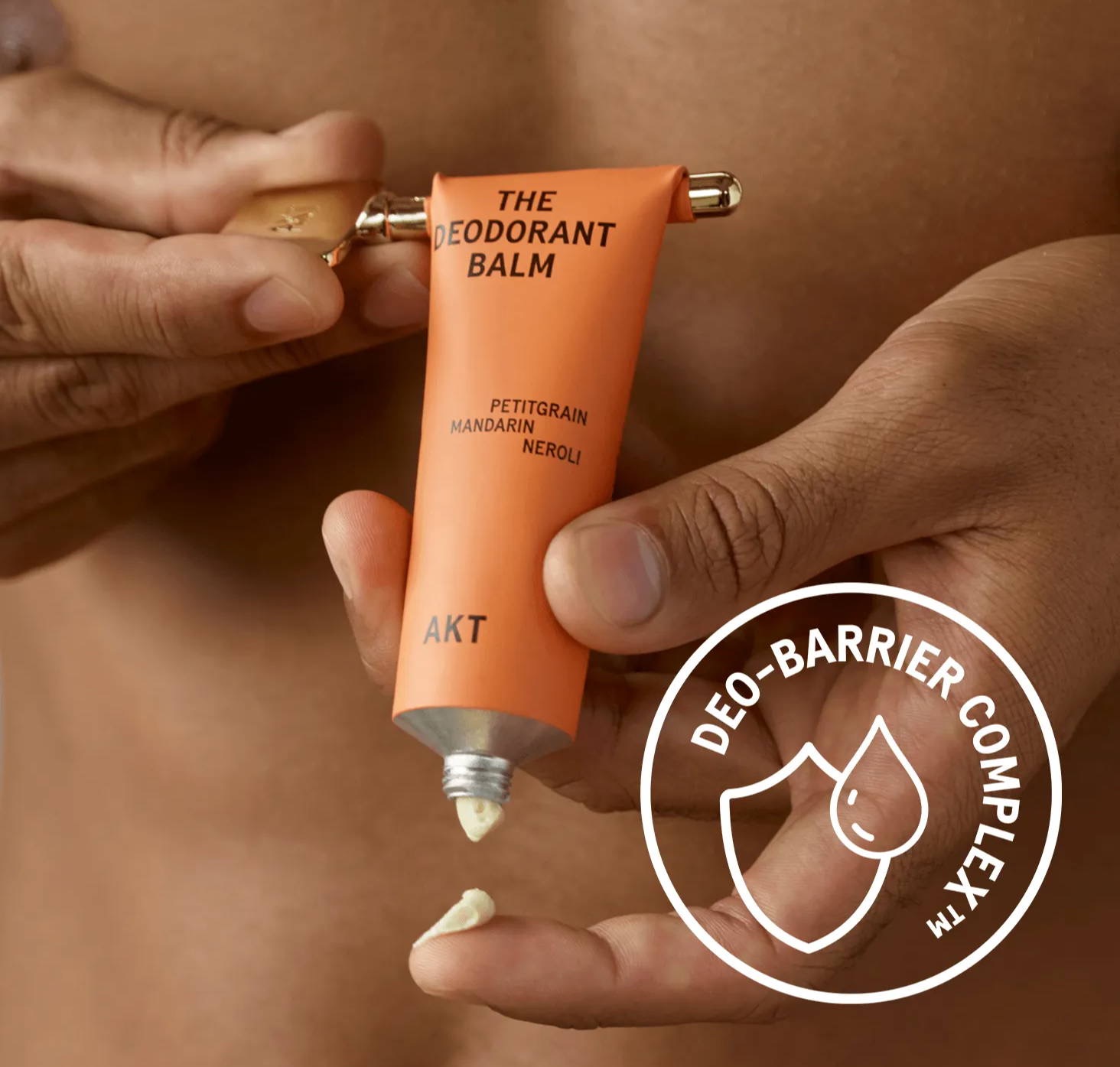 AKT Deodorant Balm in an orange tube being dispensed onto a fingertip, featuring petitgrain, mandarin, and neroli. Fearrington Village.