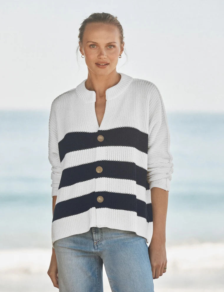 Woman wearing a navy-and-white striped cardigan with light-wash jeans in a softly lit coastal setting. Fearrington Village.
