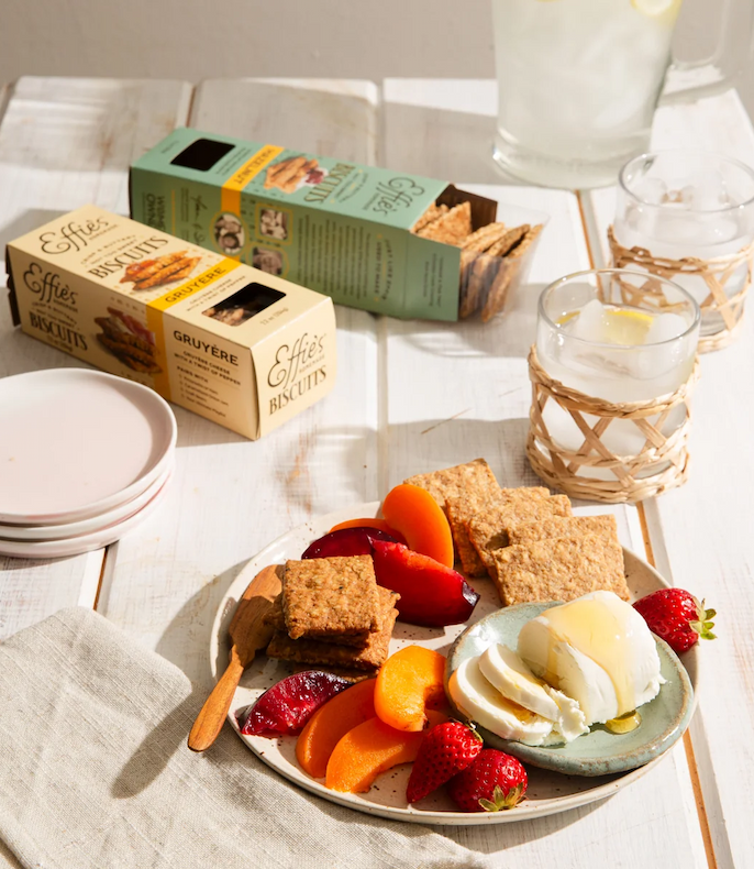 Cheese board with fresh fruit, Effie's biscuits, and soft cheese on a sunlit table. Fearrington Village.