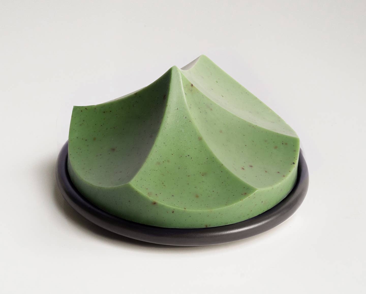 Green sculpted Ume Erode soap displayed on a small black dish.