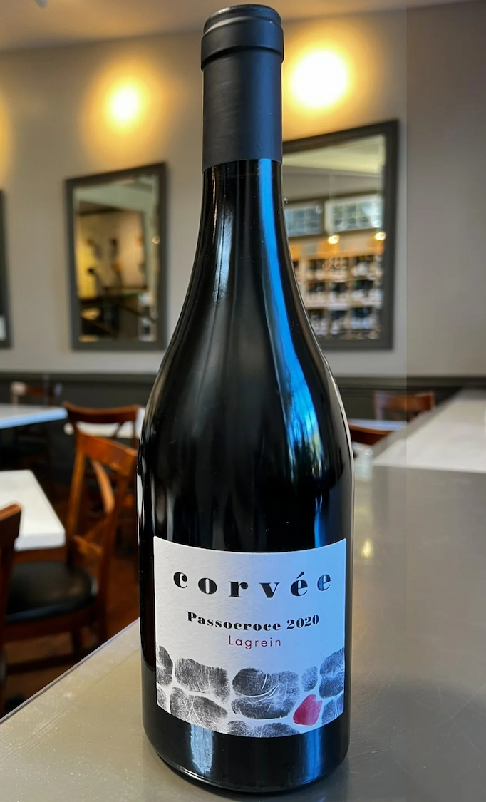 Bottle of Corvée Passocroce 2020 Lagrein wine displayed on a counter in a warmly lit wine shop. Fearrington Village.