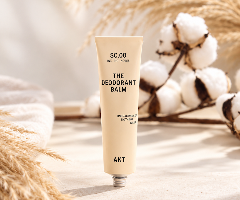 AKT unfragranced Deodorant Balm displayed with cotton and dried grasses in a bright, neutral setting. Fearrington Village.
