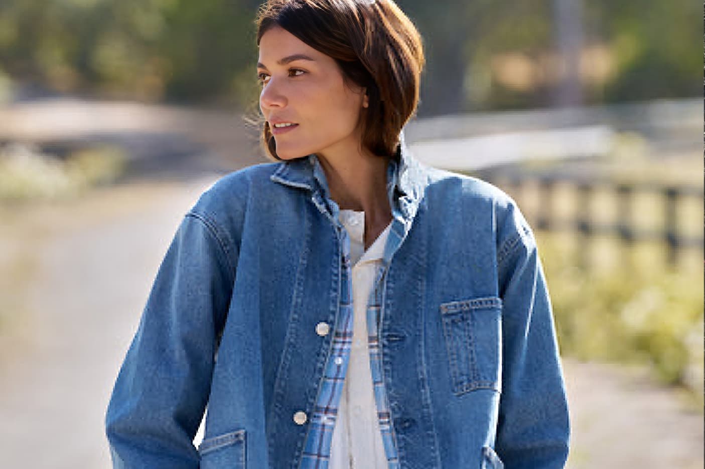 Woman wearing a relaxed blue denim jacket layered over a plaid shirt and white top outdoors. Fearrington Village.