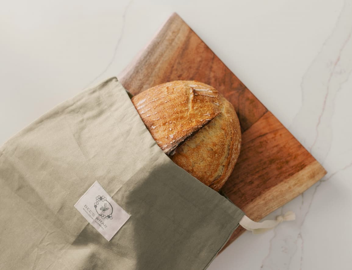 Sourdough loaf tucked into a reusable linen bread bag on a wooden board. Fearrington Village.