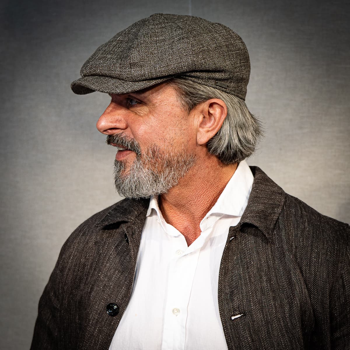 Man wearing a brown tweed flat cap with a coordinating jacket and white shirt. Fearrington Village.
