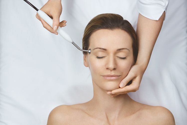 Person receiving a targeted facial treatment with a handheld skincare device during a relaxing spa service. Fearrington Village.