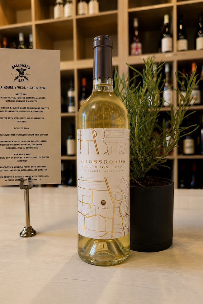 Crossroads Sauvignon Blanc displayed at Galloway’s Bar beside a rosemary plant and menu, with wine shelves in the background. Fearrington Village.