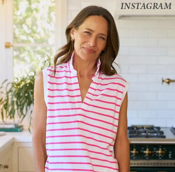 Woman wearing a white sleeveless top with bright pink stripes and a stand collar. Fearrington Village.