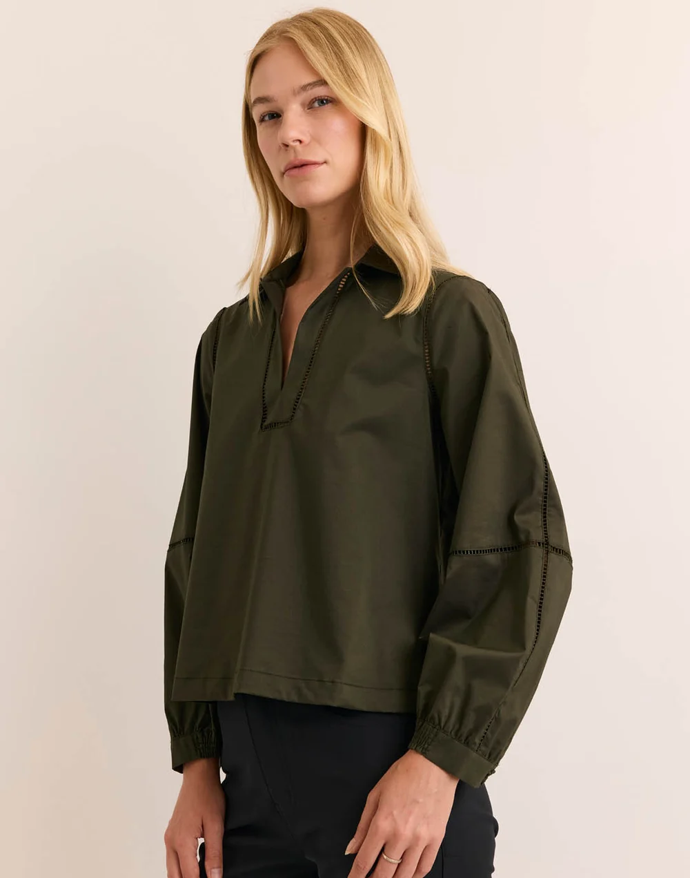 Woman modeling a dark olive green long-sleeve collared blouse with open neckline and subtle trim detailing. Fearrington Village.