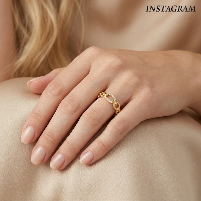Close-up of a hand wearing a gold link ring featuring an elongated pavé diamond accent, styled against soft neutral fabric to highlight its modern elegance and subtle sparkle.