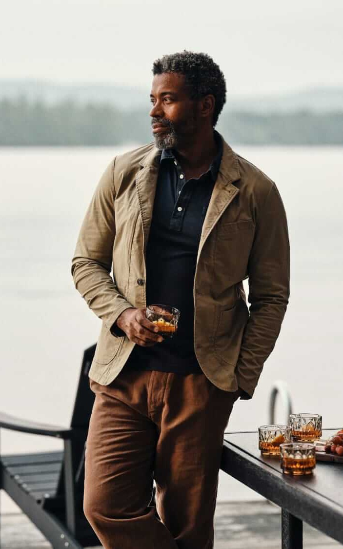 Man wearing a tan casual blazer over a navy polo shirt beside the water. Fearrington Village.