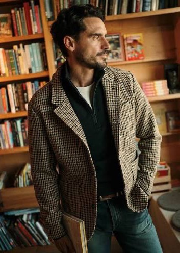 Man wearing a houndstooth blazer over a dark quarter-zip sweater in a bookstore. Fearrington Village.