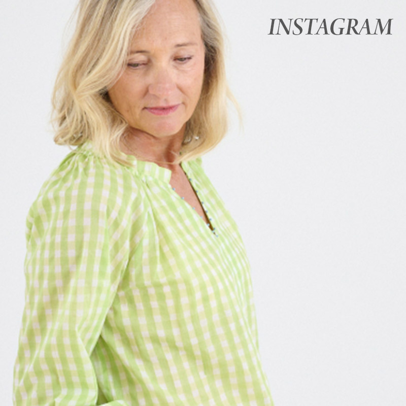 Woman wearing a light green gingham blouse looks down against a light background, with the word “Instagram” in the corner.