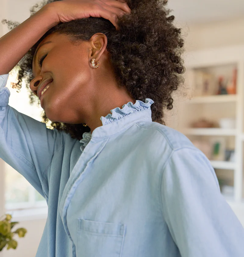 a model smiling and pulling her hair to the side