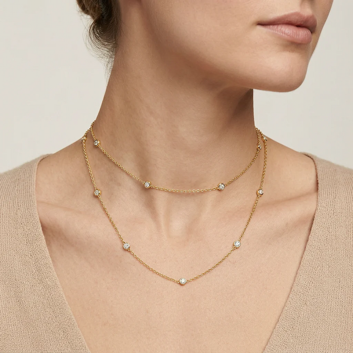 Layered gold necklace featuring bezel-set round diamonds spaced along two delicate chains, elegantly styled at the neckline for a timeless, everyday luxury look.