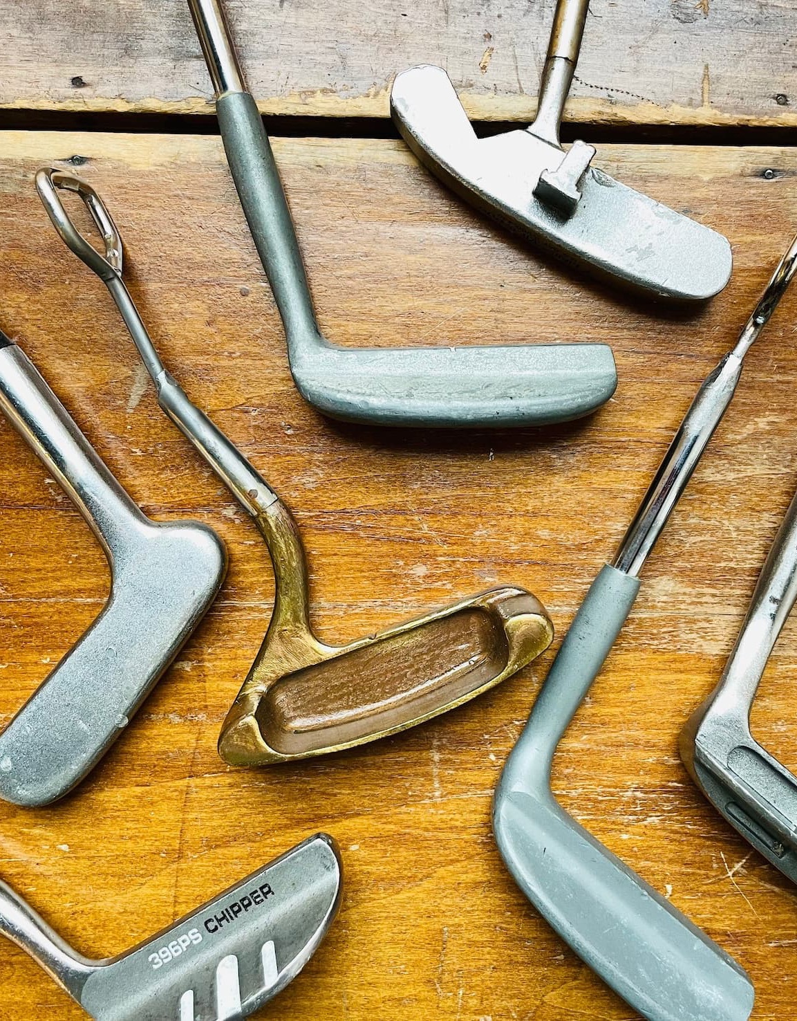 Vintage golf club bottle openers and putter-inspired bar tools arranged on a rustic wooden tabletop, Fearrington Village.