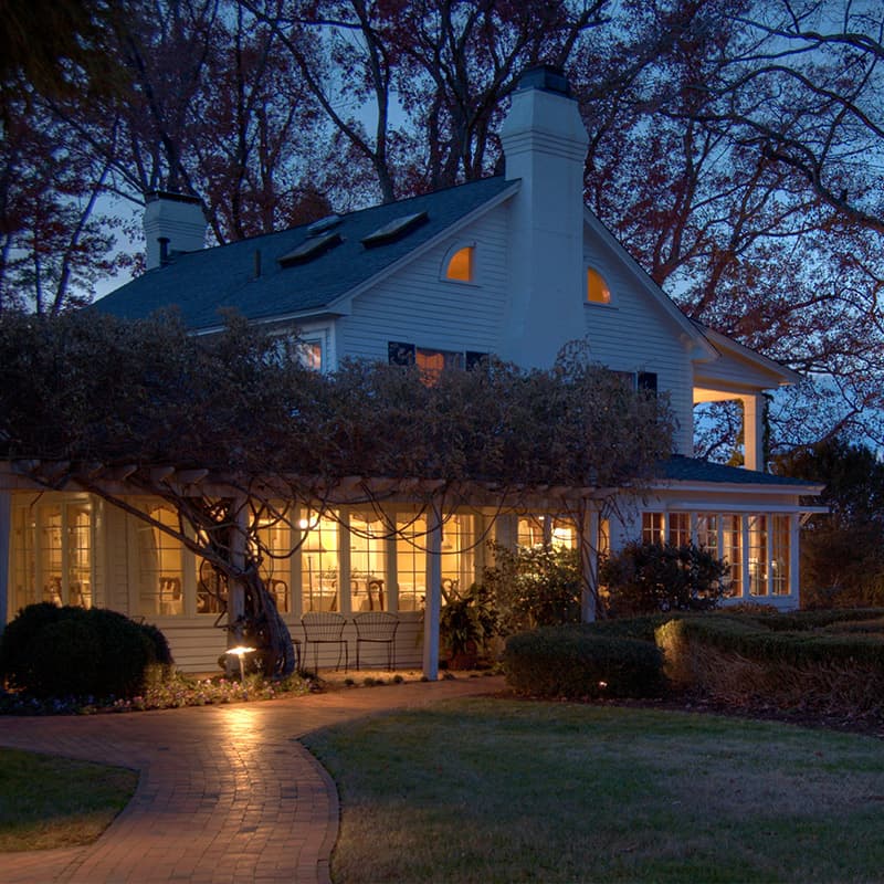 Exterior of the Fearrington House Restaurant at dusk with a lit porch and garden path.