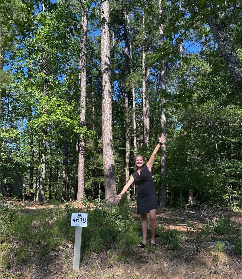 Laura Morgan showing a wooded homesite in Fearrington Village with mature trees and a lot marker. Fearrington Village.