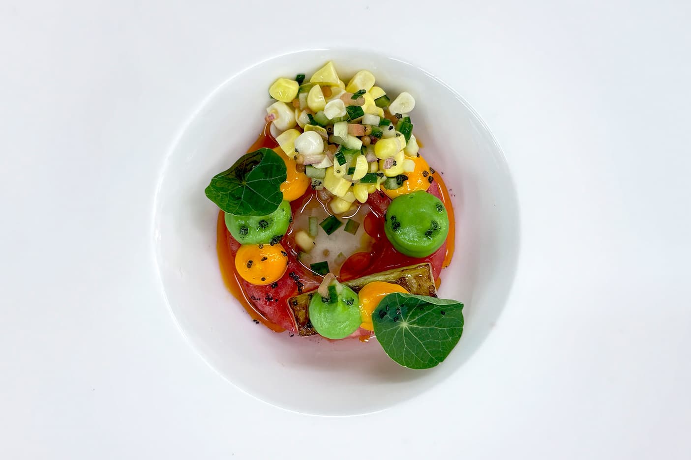 Heirloom tomato salad with sweet corn relish, grilled zucchini, herb mousse, and edible nasturtium leaves. Fearrington Village.