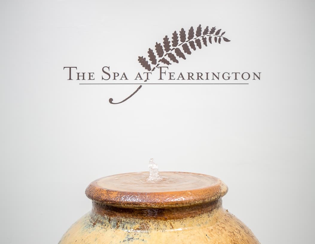 The Spa at Fearrington logo appears above a small bubbling fountain, evoking a calm and tranquil spa atmosphere.