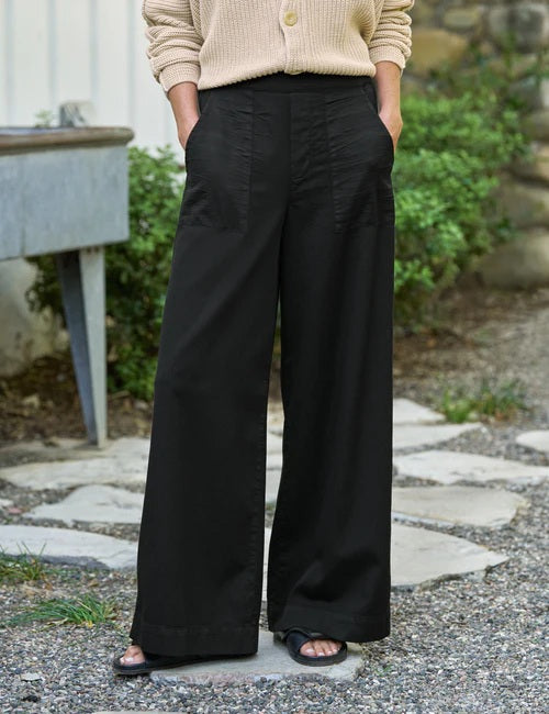 Black wide-leg pants with front patch pockets and a relaxed full-length silhouette, paired with a neutral knit sweater. Available at Dovecote at Fearrington Village.