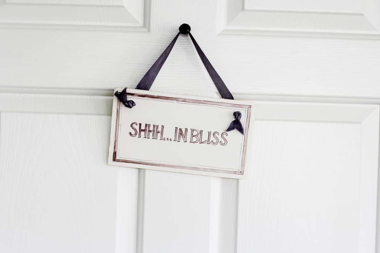 A small sign hanging on a white door reads “Shhh… in bliss,” suggesting a quiet spa or relaxation space.