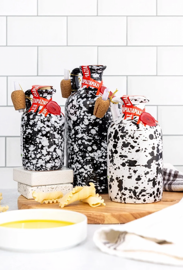 Black-and-white splatter-patterned ceramic bottles with cork pourers, styled with pasta and olive oil in a bright kitchen setting. Fearrington Village.