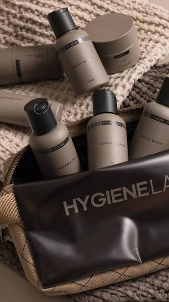 HygieneLab personal-care essentials, including shampoo, conditioner and face wash, arranged in a travel bag on a textured knit background. Fearrington Village.