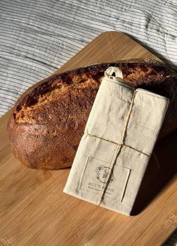 Rustic bread loaf with a reusable beeswax bread wrap on a wooden cutting board. Fearrington Village.