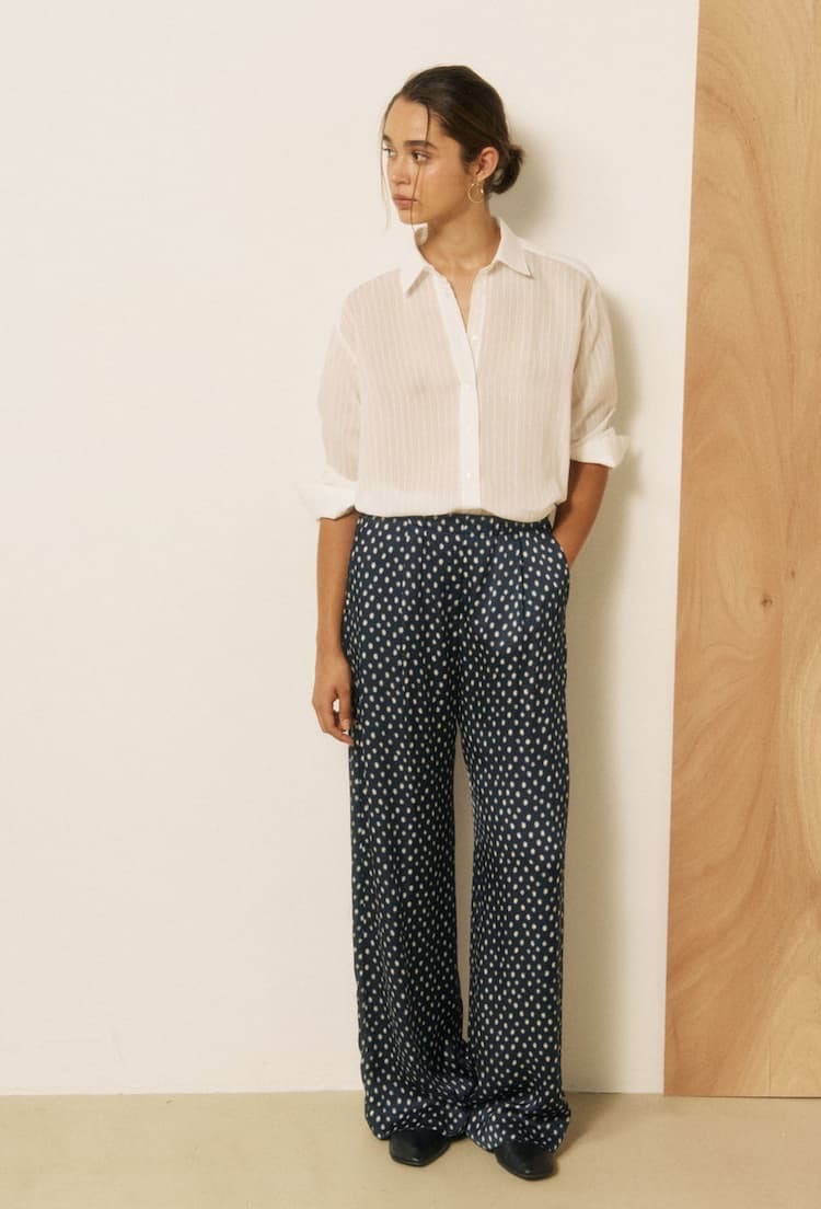 Woman wearing a white button-down shirt with navy wide-leg patterned trousers. Fearrington Village.