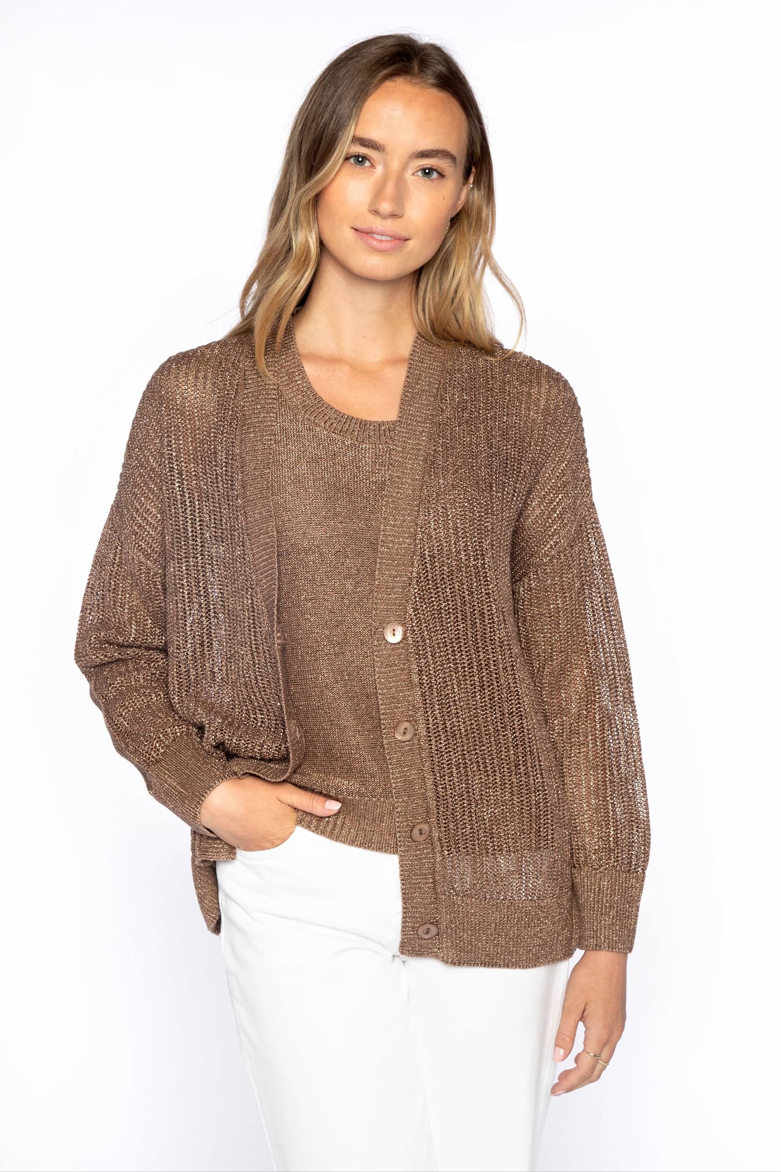 Woman wearing a textured brown knit cardigan layered over a matching top, paired with light trousers against a neutral background.