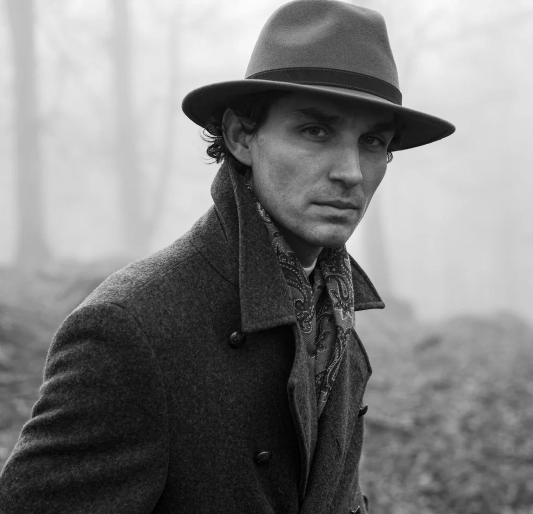 Man wearing a wide-brim felt hat, wool coat and patterned scarf in a black-and-white portrait. Fearrington Village.