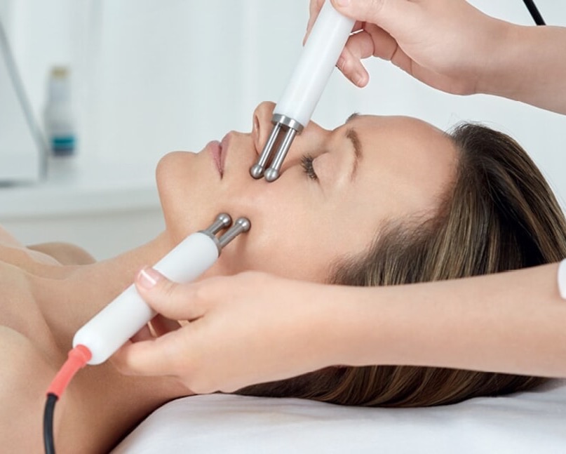 Person enjoying a professional facial treatment using dual handheld skincare devices at a luxury spa. Fearrington Village.