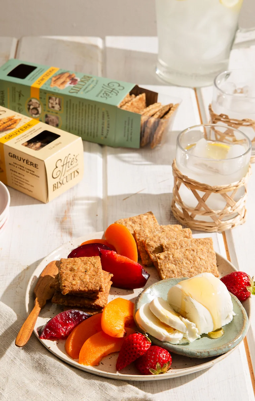Plate of fresh mozzarella, seasonal fruit, and Effie's Biscuits served with crisp crackers and refreshing drinks on a sunlit table. Fearrington Village.