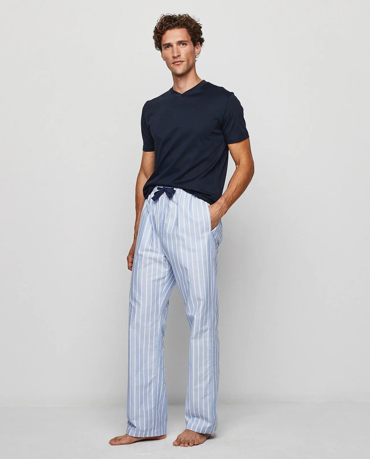 Man wearing a navy V-neck T-shirt with blue-and-white striped lounge pants. Fearrington Village.