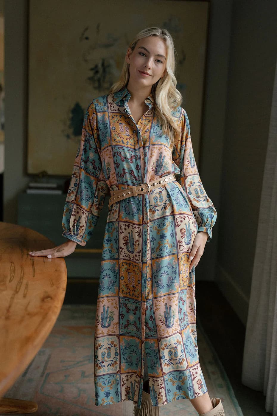 A woman models a long button-front shirt dress in a colorful patchwork botanical print, styled with a studded tan belt. Fearrington Village.