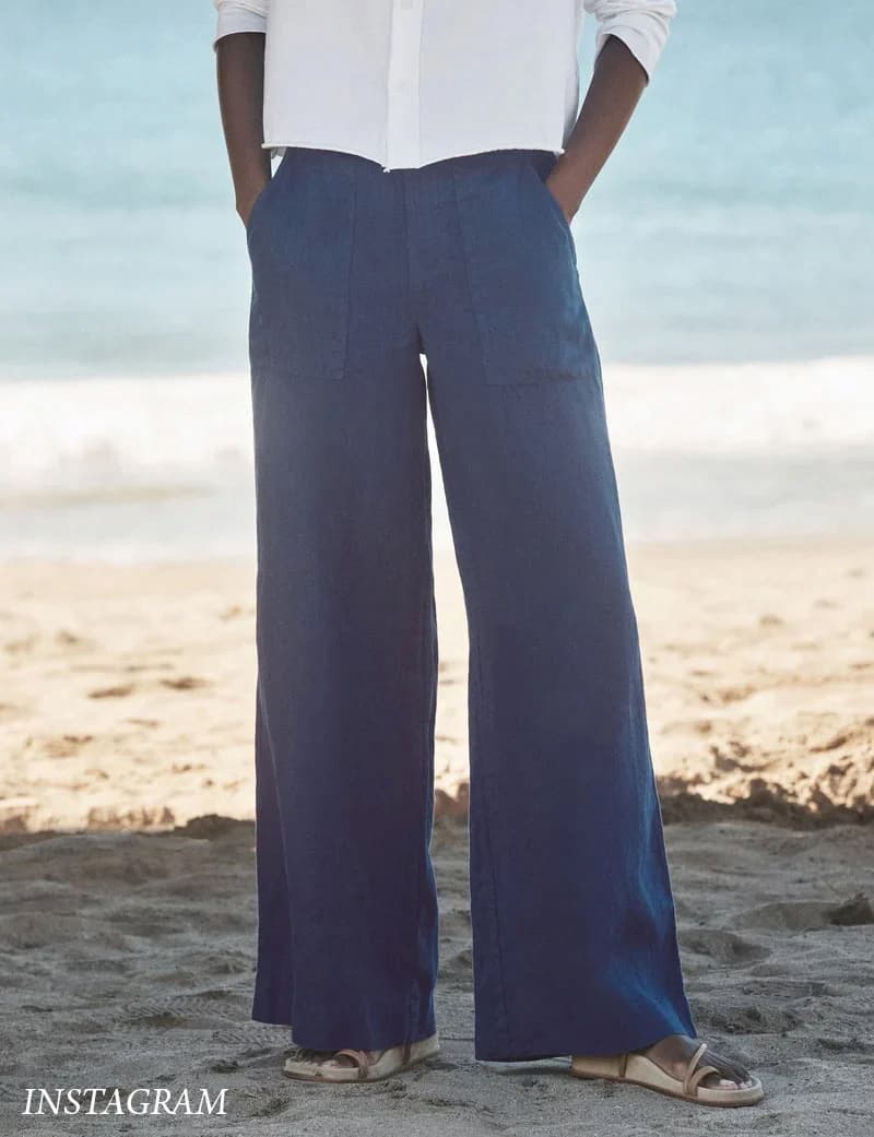Navy wide-leg linen pants with front patch pockets styled on a beach with a white button-down shirt and sandals. Fearrington Village.