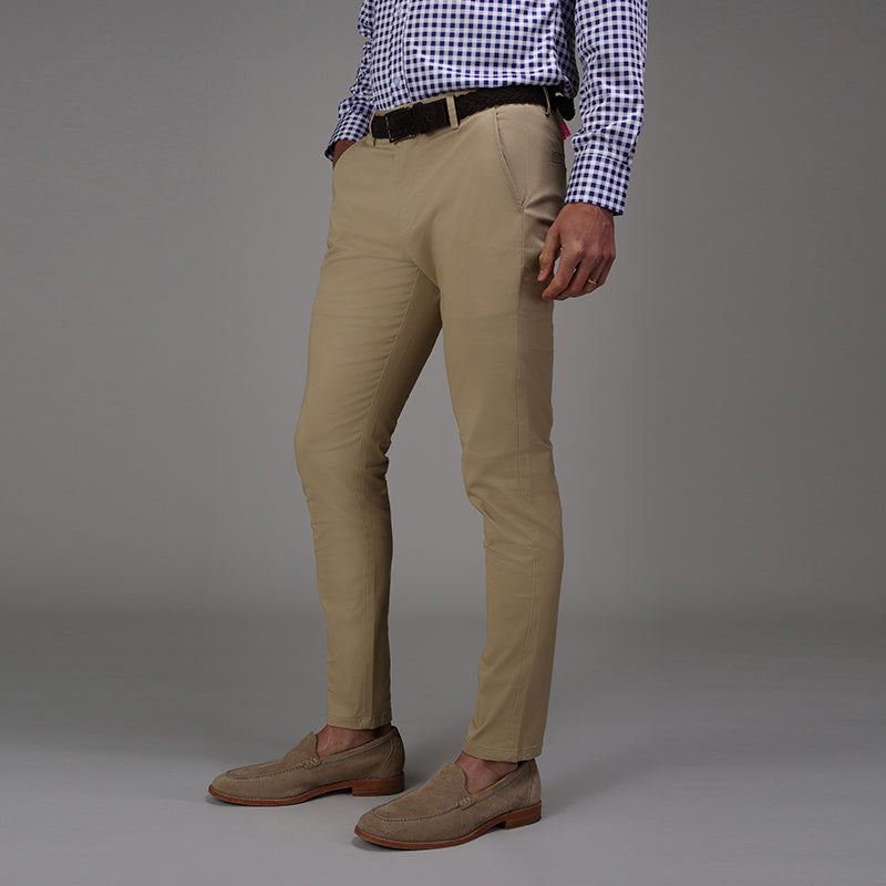 A man wearing slim-fit khaki trousers with a navy gingham shirt and brown suede loafers, photographed from waist down.