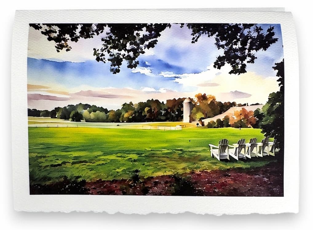 Watercolor-style card depicting a wide green pasture under a soft sky, with a barn and silo in the distance and a row of white Adirondack chairs set beneath leafy trees, printed on textured paper with deckled edges.