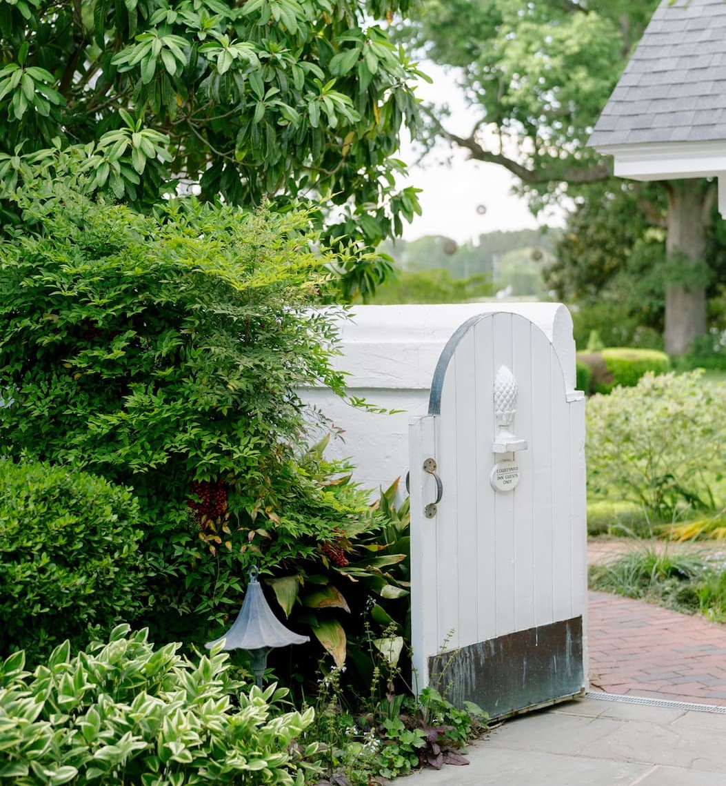 White garden gate opening onto a lush courtyard garden at The Fearrington House Inn. Fearrington Village.