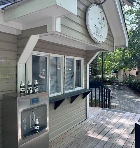 The Roost beer garden features a convenient outdoor service window and self-serve beer tap station, with a shaded deck and patio seating nestled among the trees. Fearrington Village.