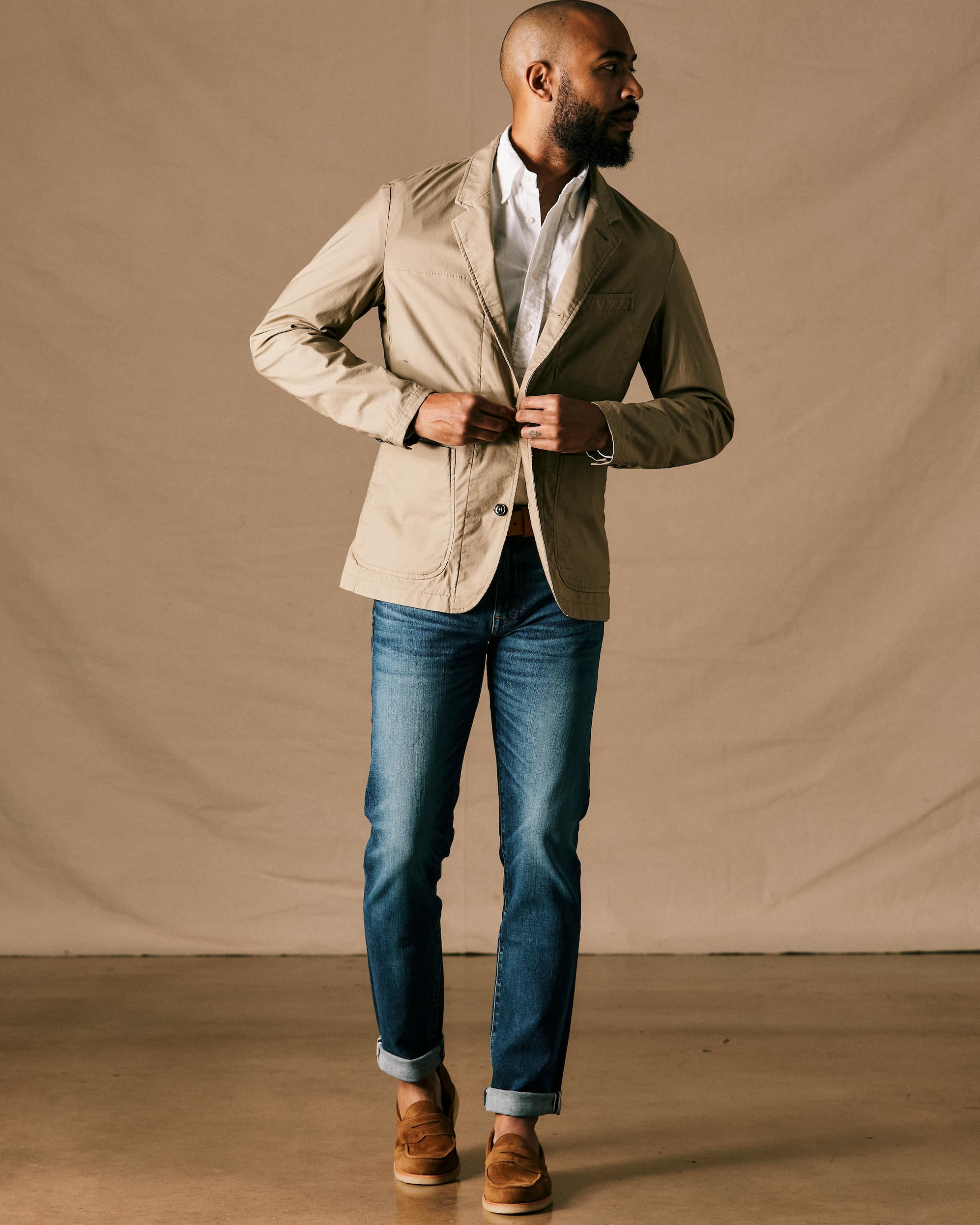 A man models a tan casual blazer over a crisp white shirt with cuffed blue jeans and brown loafers. Fearrington Village.