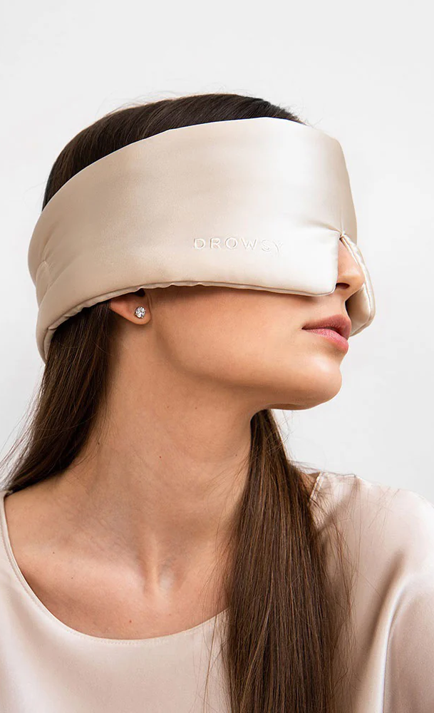 Woman wearing a beige Drowsy silk sleep mask, shown in profile against a neutral background.