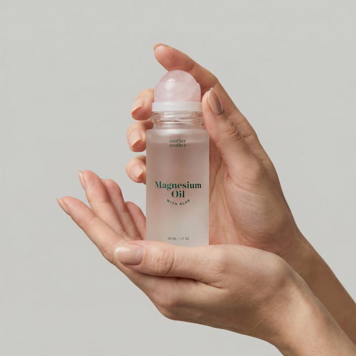 Hands holding a roll-on bottle of magnesium oil with aloe for topical skincare and muscle recovery. Fearrington Village.