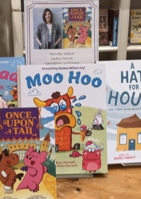 Display of children's books, including Moo Hoo and Once Upon a Tail, featured on a bookstore table with a local author display in the background. Fearrington Village.