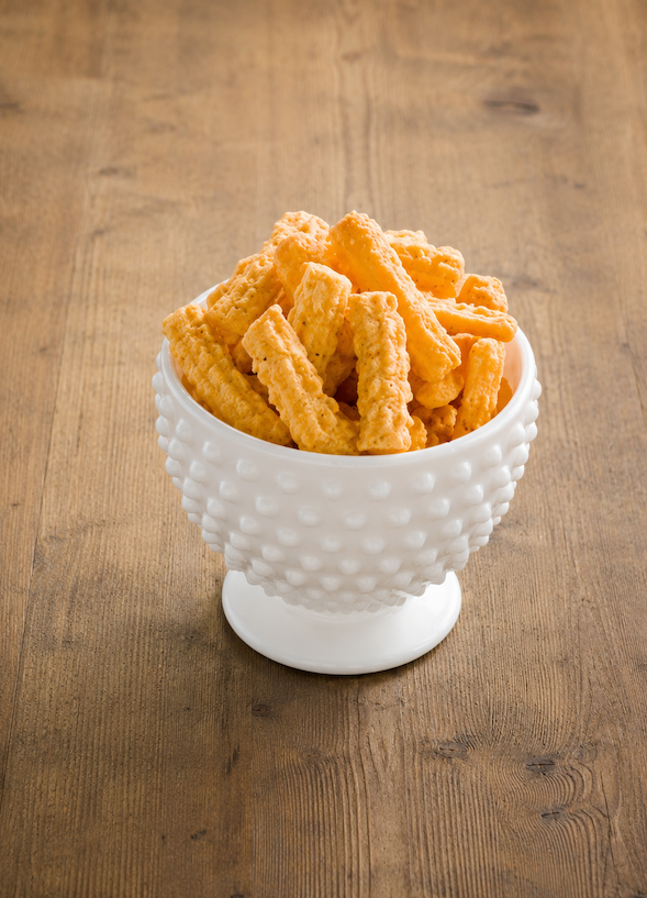 Bowl of crunchy cheese straws served in a white hobnail pedestal bowl on a rustic wooden table. Fearrington Village.