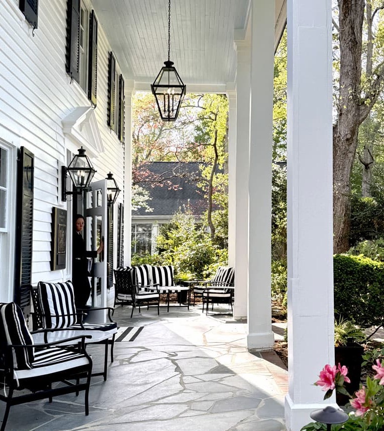 Front porch of The Fearrington House Inn with black-and-white striped seating, lanterns, and surrounding gardens. Fearrington Village.