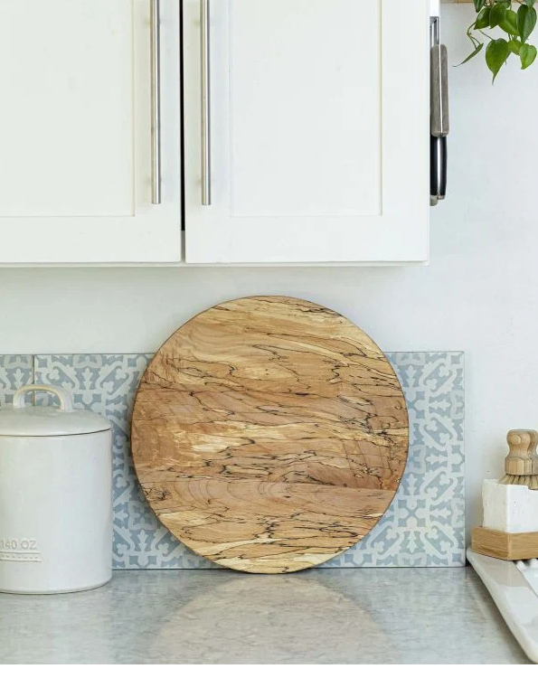 Round handcrafted wooden serving board with distinctive natural grain displayed in a bright kitchen. Fearrington Village.